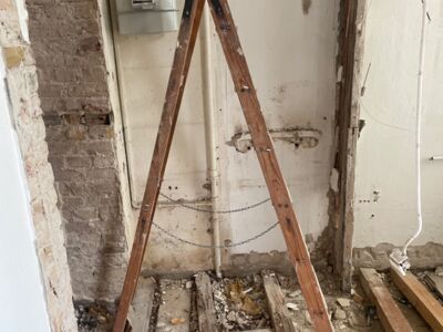 Leiter steht in einem renovierungsbedürftigem Wohnraum.